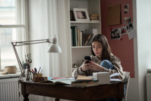 Teen scrolling through social media on her phone 